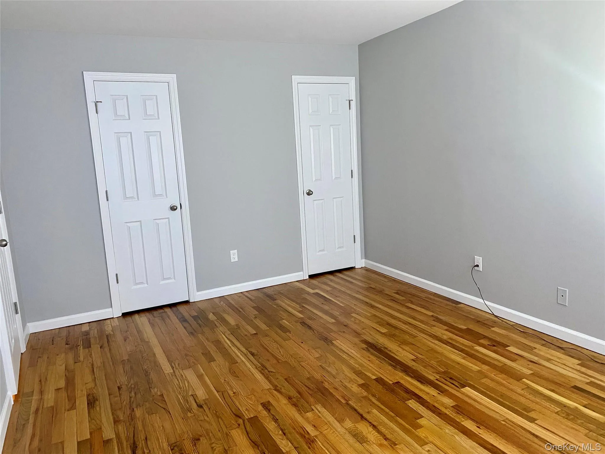 Unfurnished bedroom with hardwood / wood-style flooring. Two closets Unfurnished bedroom with hardwood / wood-style flooring. Two closets