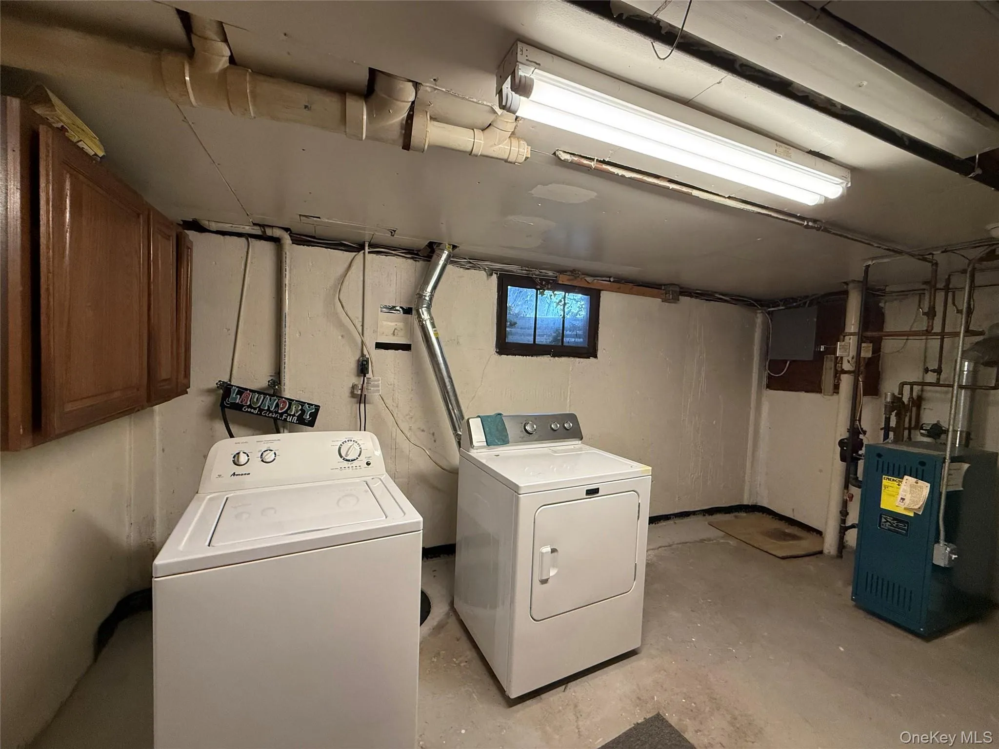 Washroom with unfinished concrete flooring, a heating unit, and washer and clothes dryer Washroom with unfinished concrete flooring, a heating unit, and washer and clothes dryer