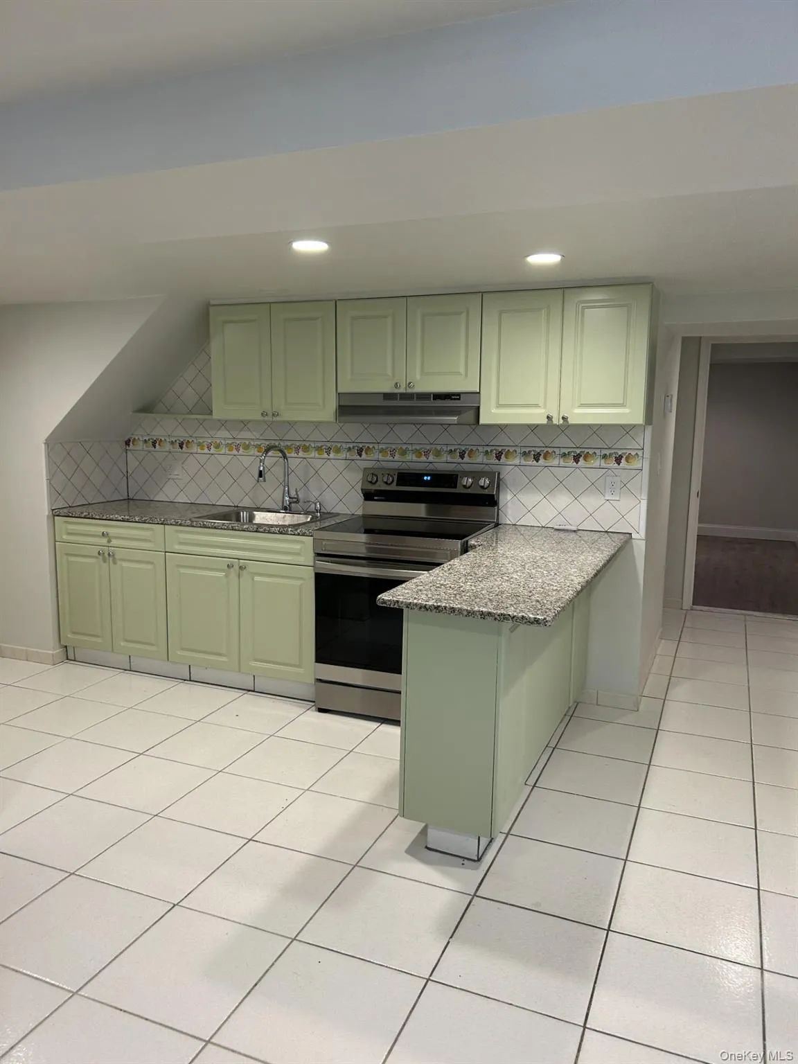Kitchen featuring stainless steel electric range oven, light stone counters, green cabinets, under cabinet range hood, and a peninsula Kitchen featuring stainless steel electric range oven, light stone counters, green cabinets, under cabinet range hood, and a peninsula