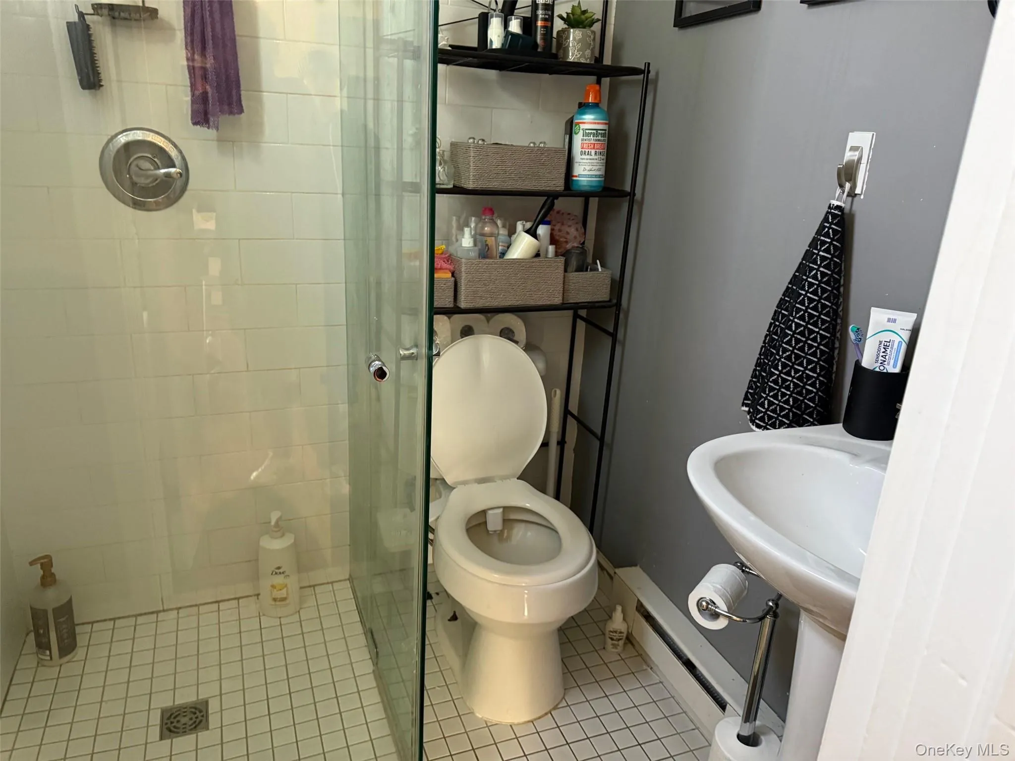 Full bathroom with a shower stall, a baseboard heating unit, and tile patterned flooring Full bathroom with a shower stall, a baseboard heating unit, and tile patterned flooring