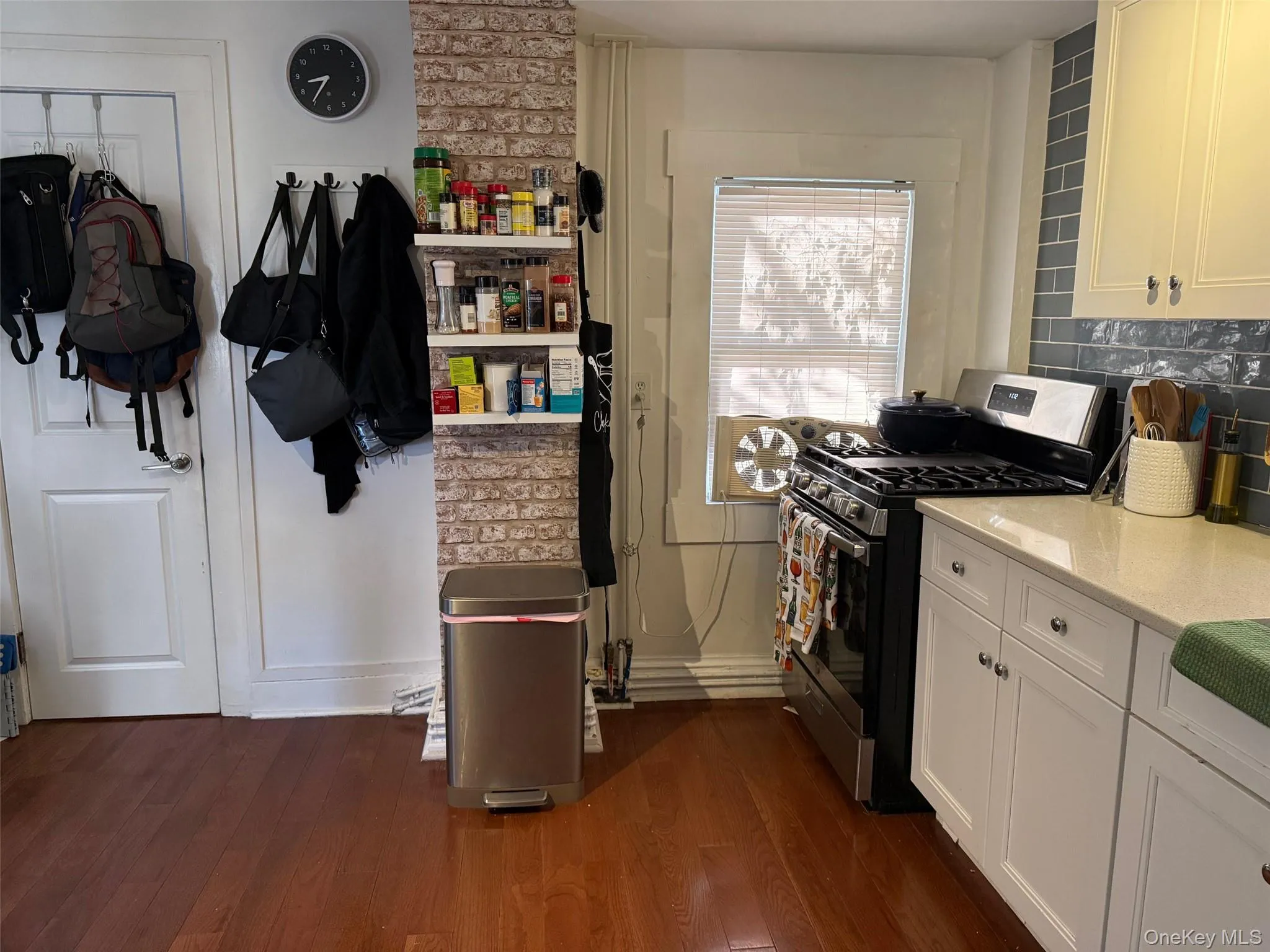 Kitchen featuring stainless steel gas stove, dark wood-type flooring, light stone countertops, and white cabinets Kitchen featuring stainless steel gas stove, dark wood-type flooring, light stone countertops, and white cabinets