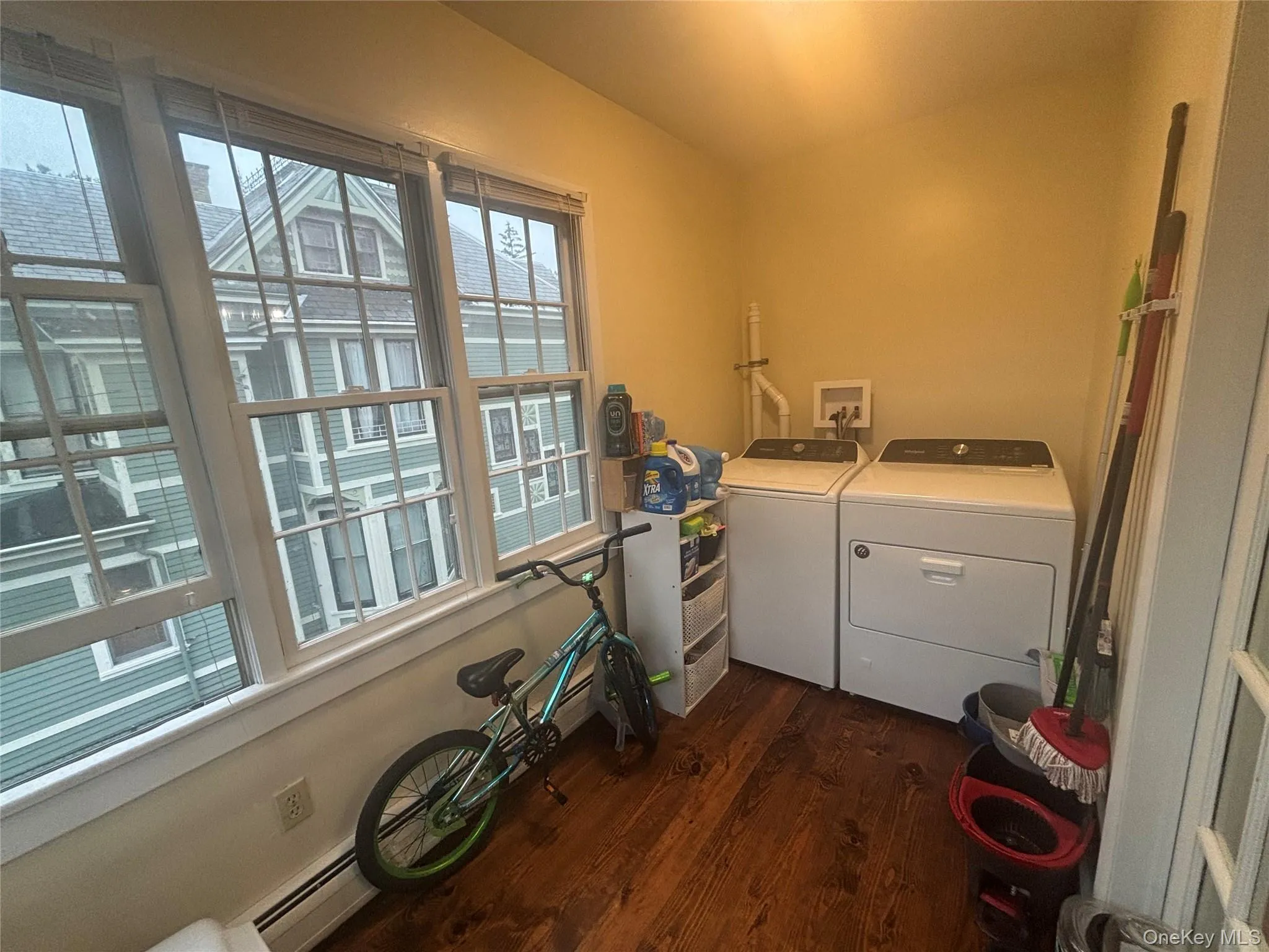 Laundry area with dark wood finished floors, a baseboard radiator, and washer and clothes dryer Laundry area with dark wood finished floors, a baseboard radiator, and washer and clothes dryer