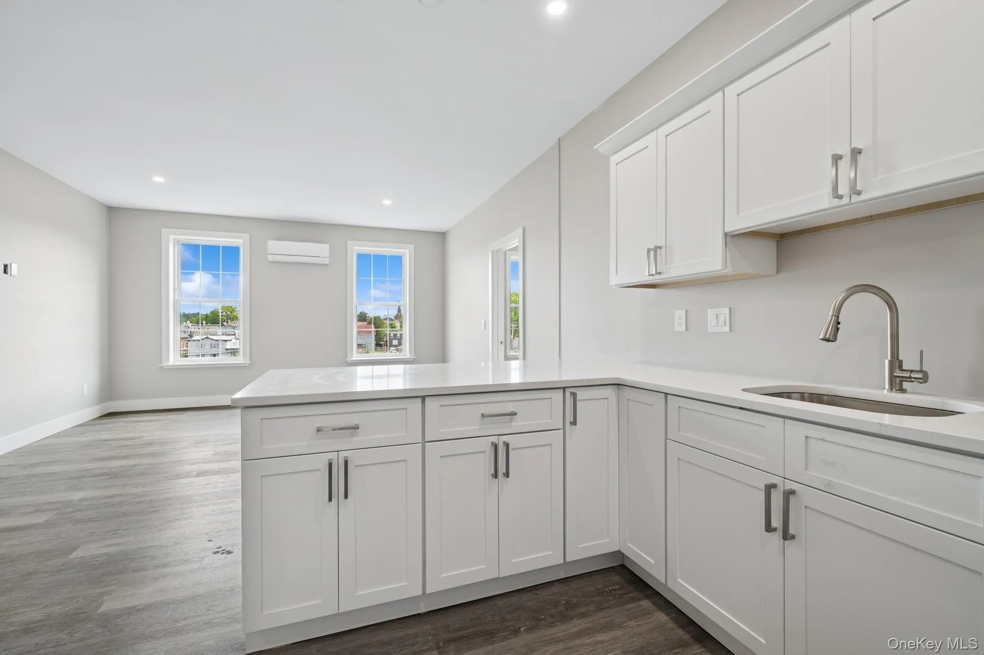 Kitchen featuring white cabinets, dark wood finished floors, light stone countertops, recessed lighting, and a peninsula Kitchen featuring white cabinets, dark wood finished floors, light stone countertops, recessed lighting, and a peninsula