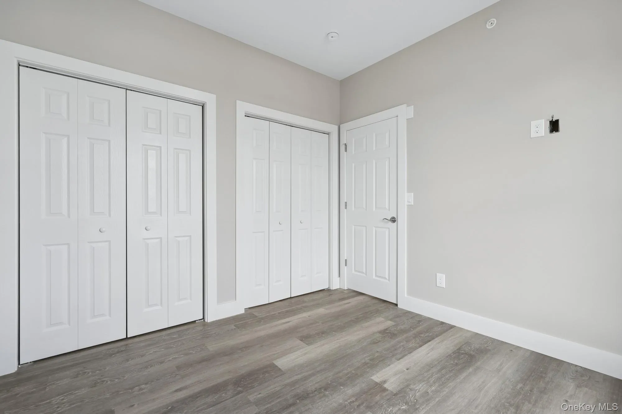 Unfurnished bedroom featuring two closets and wood finished floors Unfurnished bedroom featuring two closets and wood finished floors