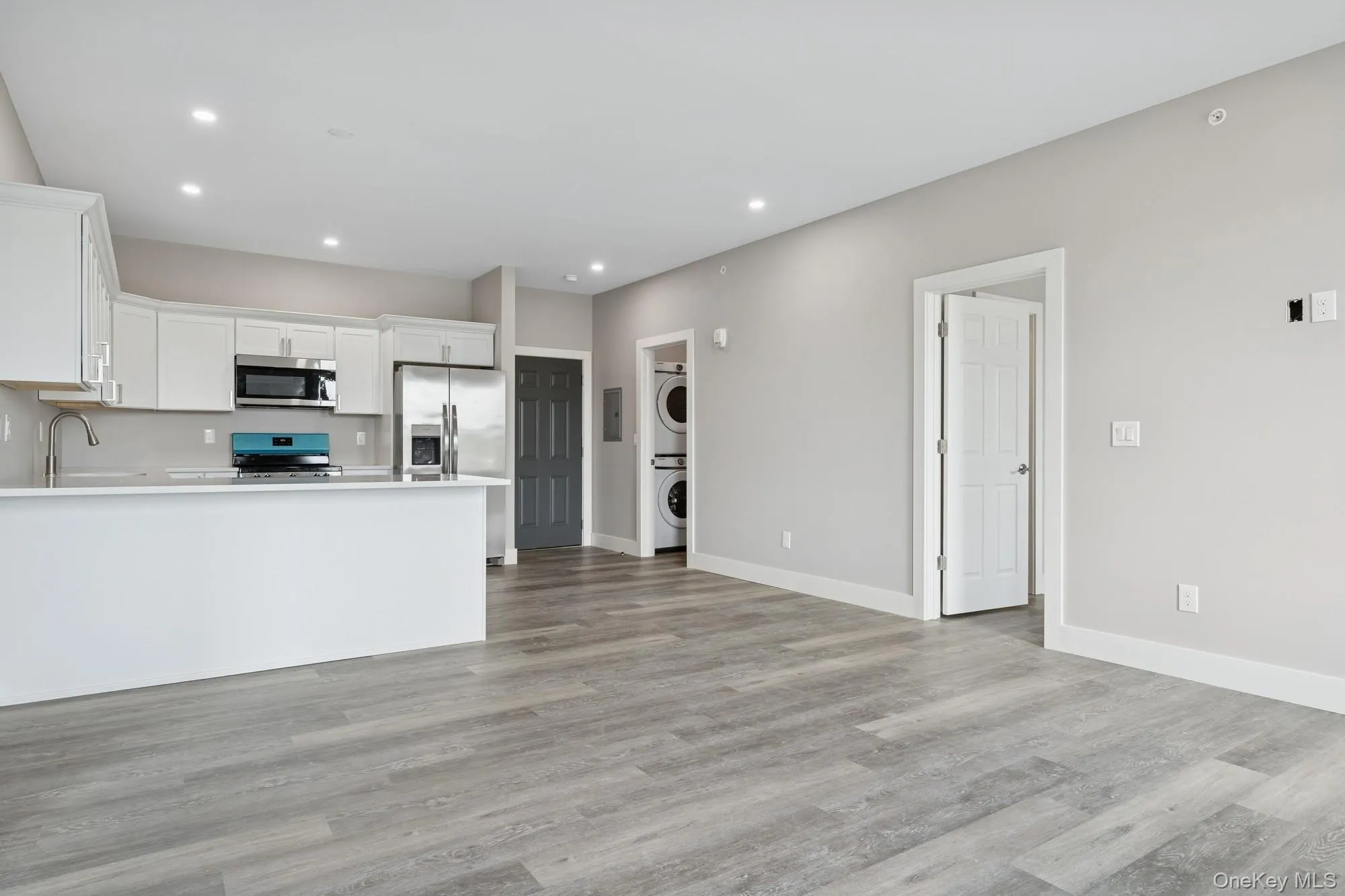 Kitchen with white cabinets, appliances with stainless steel finishes, recessed lighting, estacked washer and dryer, and light wood finished floors Kitchen with white cabinets, appliances with stainless steel finishes, recessed lighting, estacked washer and dryer, and light wood finished floors