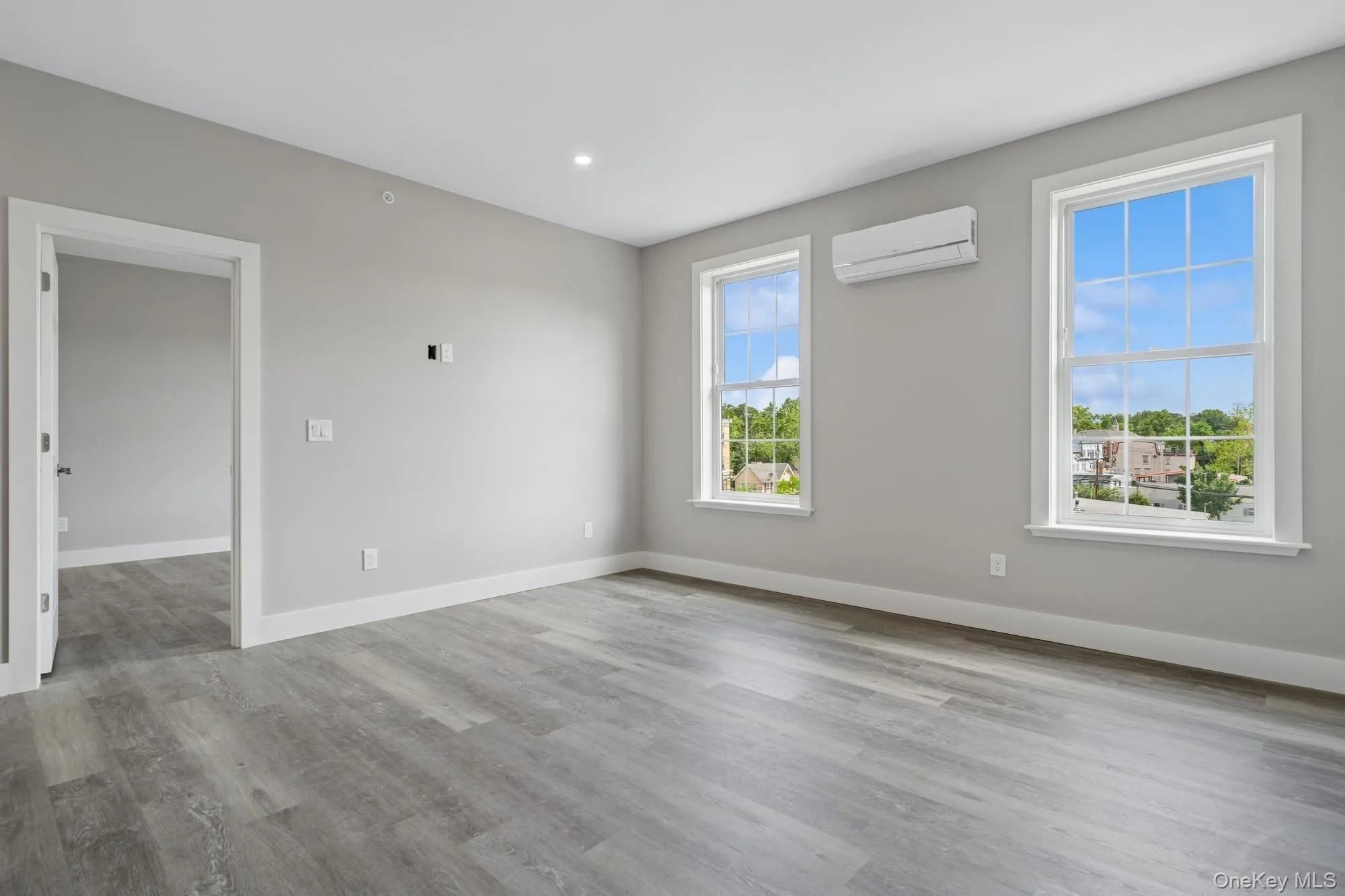Empty room featuring light wood-type flooring, a wall mounted AC, and recessed lighting Empty room featuring light wood-type flooring, a wall mounted AC, and recessed lighting