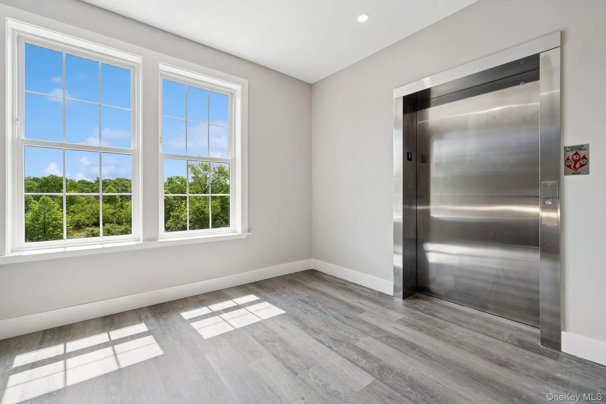 Unfurnished room featuring elevator and light wood-type flooring Unfurnished room featuring elevator and light wood-type flooring