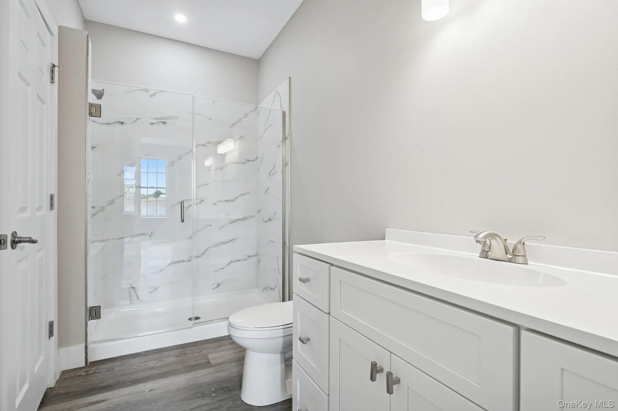 Bathroom with vanity, dark wood-type flooring, and a marble finish shower Bathroom with vanity, dark wood-type flooring, and a marble finish shower