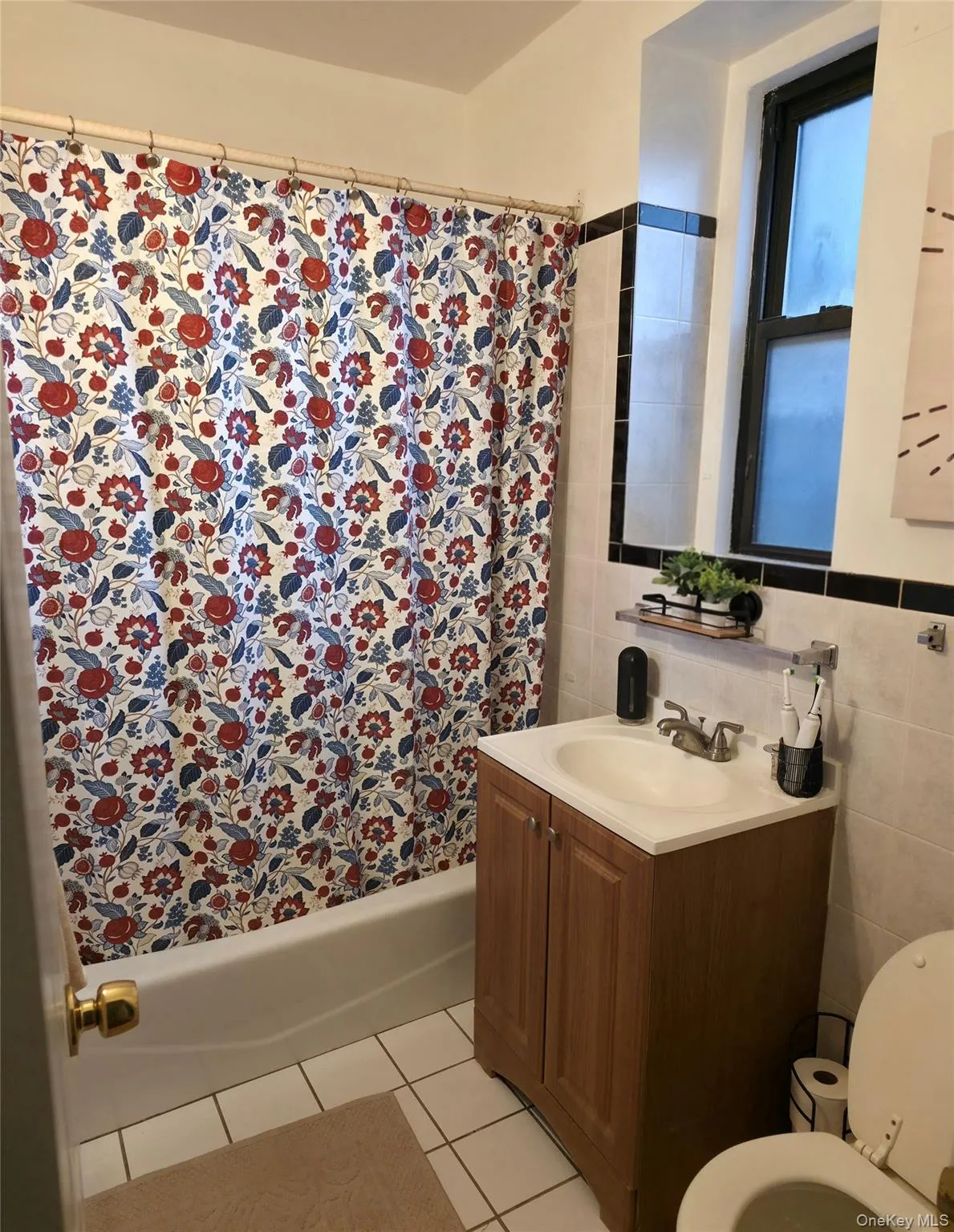 Bathroom with vanity, tile walls, light tile patterned floors, and shower / bath combination with curtain Bathroom with vanity, tile walls, light tile patterned floors, and shower / bath combination with curtain