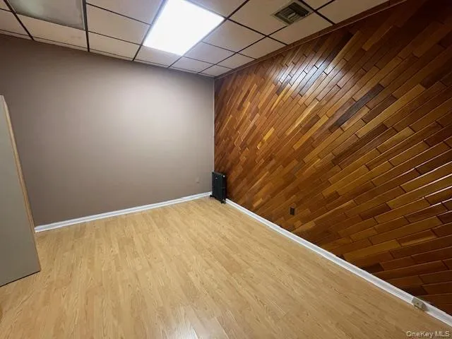 Spare room with wooden walls, a paneled ceiling, an accent wall, and light wood-style flooring Spare room with wooden walls, a paneled ceiling, an accent wall, and light wood-style flooring