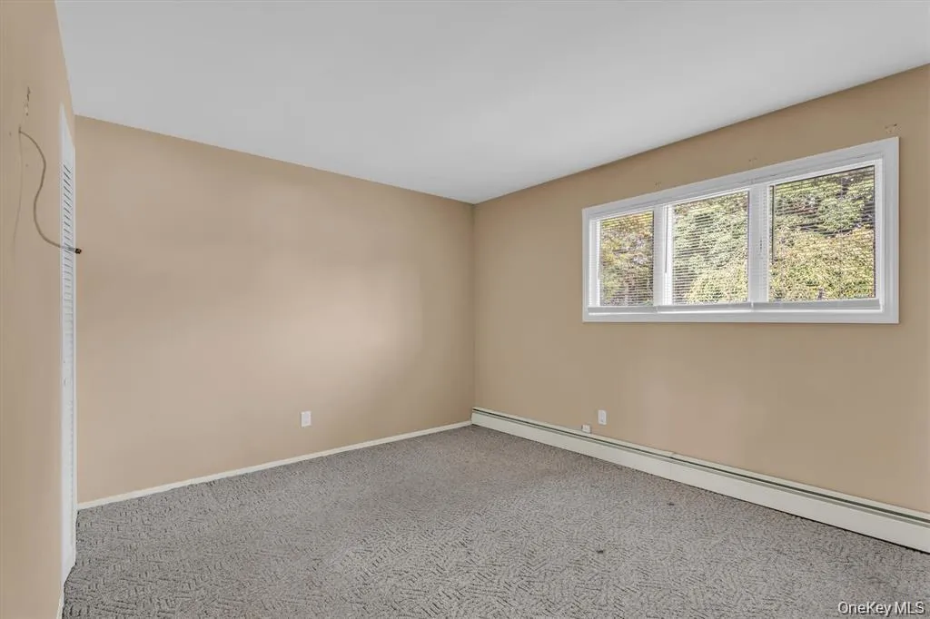 Empty room featuring baseboard heating and carpet floors Empty room featuring baseboard heating and carpet floors