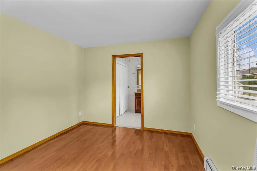 Unfurnished room with light wood-style flooring and baseboard heating Unfurnished room with light wood-style flooring and baseboard heating