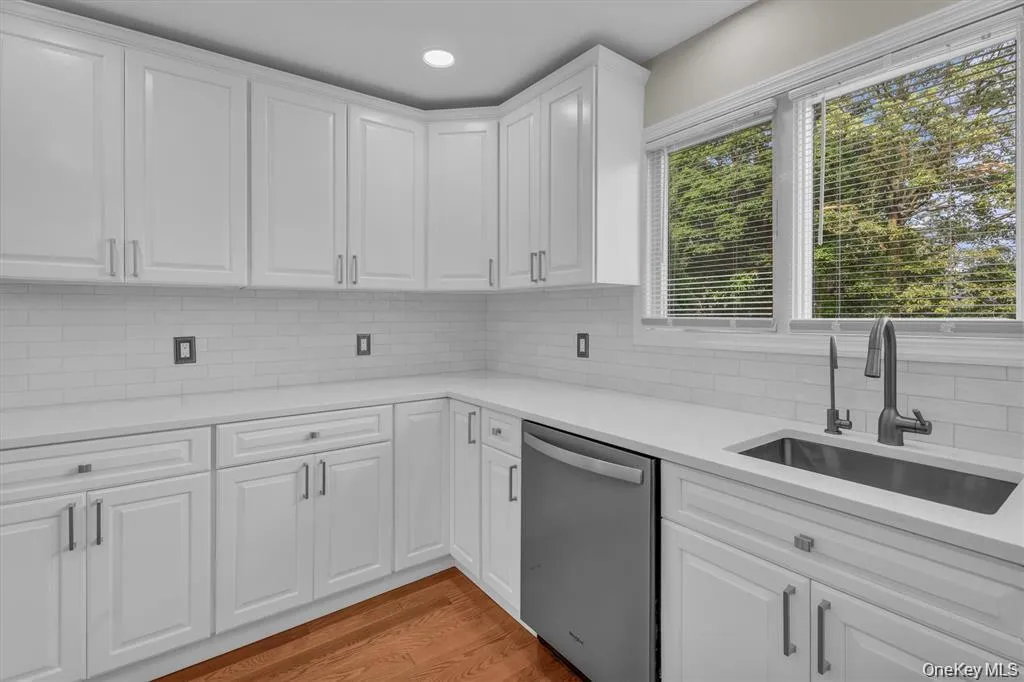 Kitchen with white cabinetry, light stone countertops, stainless steel dishwasher, light wood finished floors, and recessed lighting Kitchen with white cabinetry, light stone countertops, stainless steel dishwasher, light wood finished floors, and recessed lighting