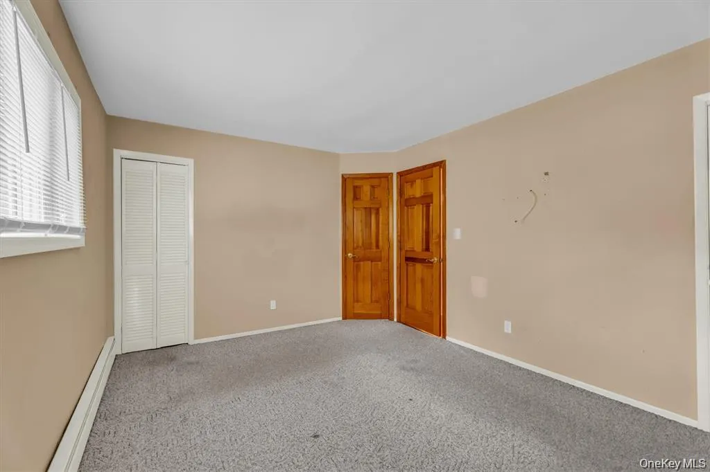 Carpeted empty room featuring a baseboard heating unit and baseboards Carpeted empty room featuring a baseboard heating unit and baseboards