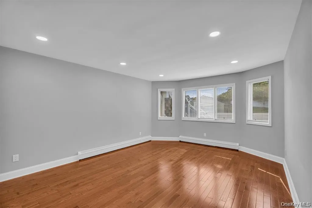 Empty room featuring a baseboard heating unit, light wood-style floors, and recessed lighting Empty room featuring a baseboard heating unit, light wood-style floors, and recessed lighting