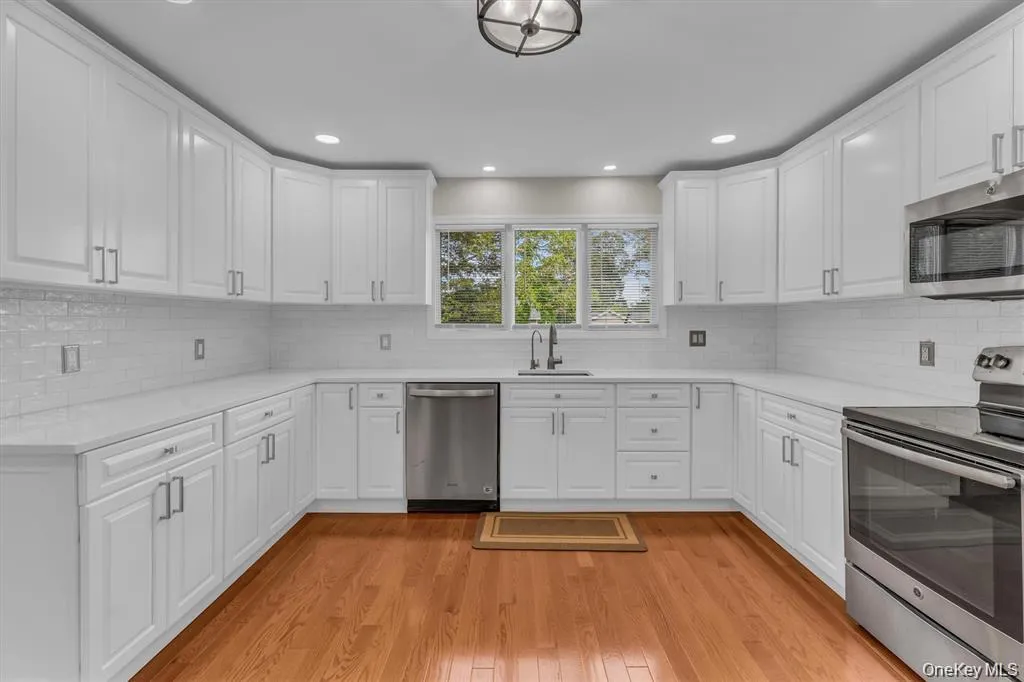 Kitchen featuring stainless steel appliances, white cabinets, light stone counters, light wood-style floors, and recessed lighting Kitchen featuring stainless steel appliances, white cabinets, light stone counters, light wood-style floors, and recessed lighting