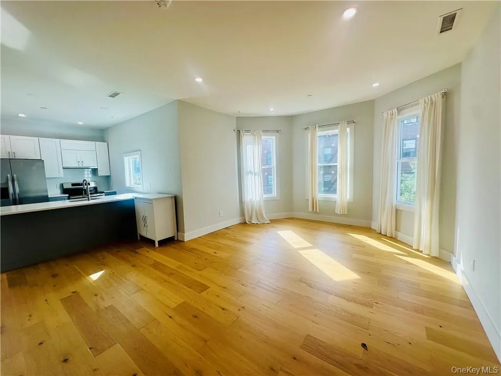 Kitchen with white cabinets, light hardwood / wood-style floors, black fridge with ice dispenser, and sink Kitchen with white cabinets, light hardwood / wood-style floors, black fridge with ice dispenser, and sink