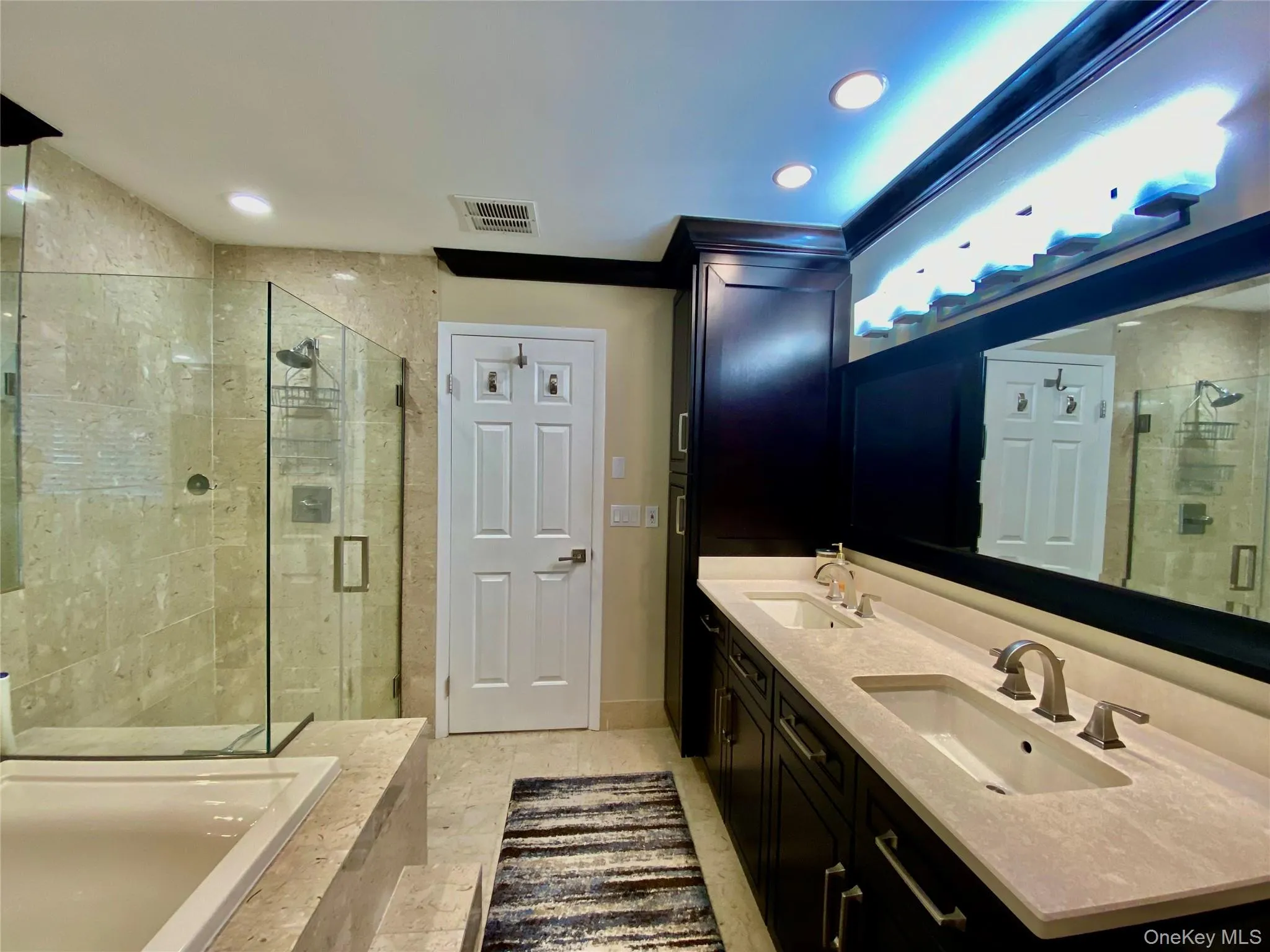 Full bathroom featuring double vanity, a stall shower, recessed lighting, and tiled bath Full bathroom featuring double vanity, a stall shower, recessed lighting, and tiled bath