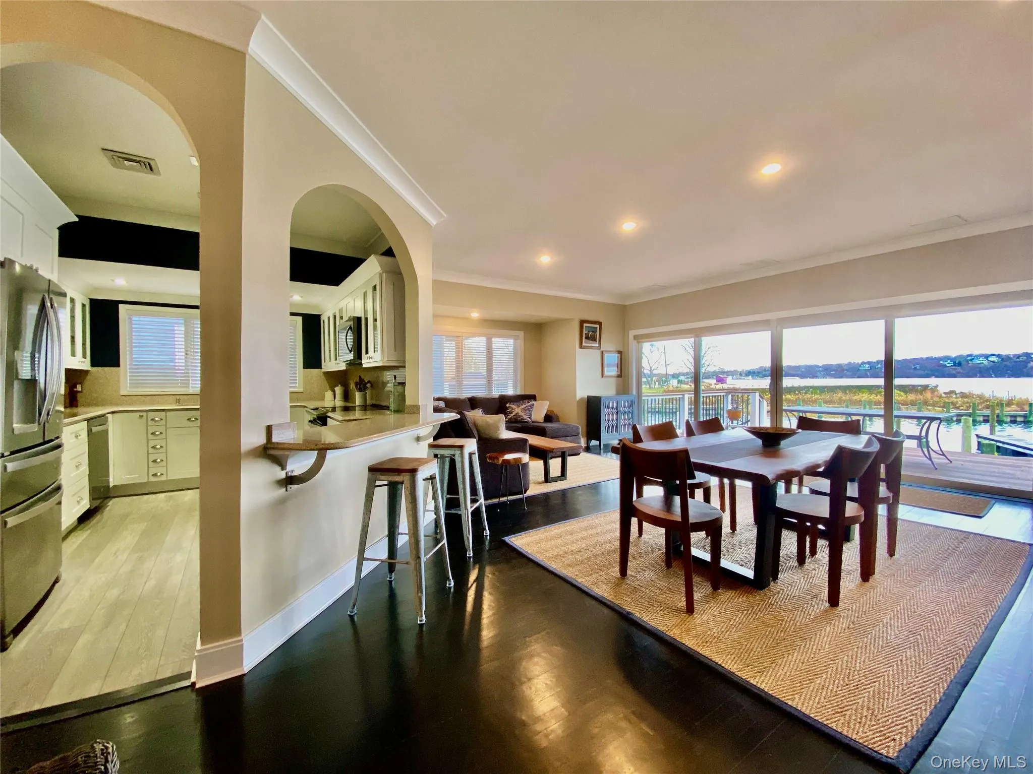 Dining space with dark wood-style flooring, ornamental molding, arched walkways, and recessed lighting Dining space with dark wood-style flooring, ornamental molding, arched walkways, and recessed lighting
