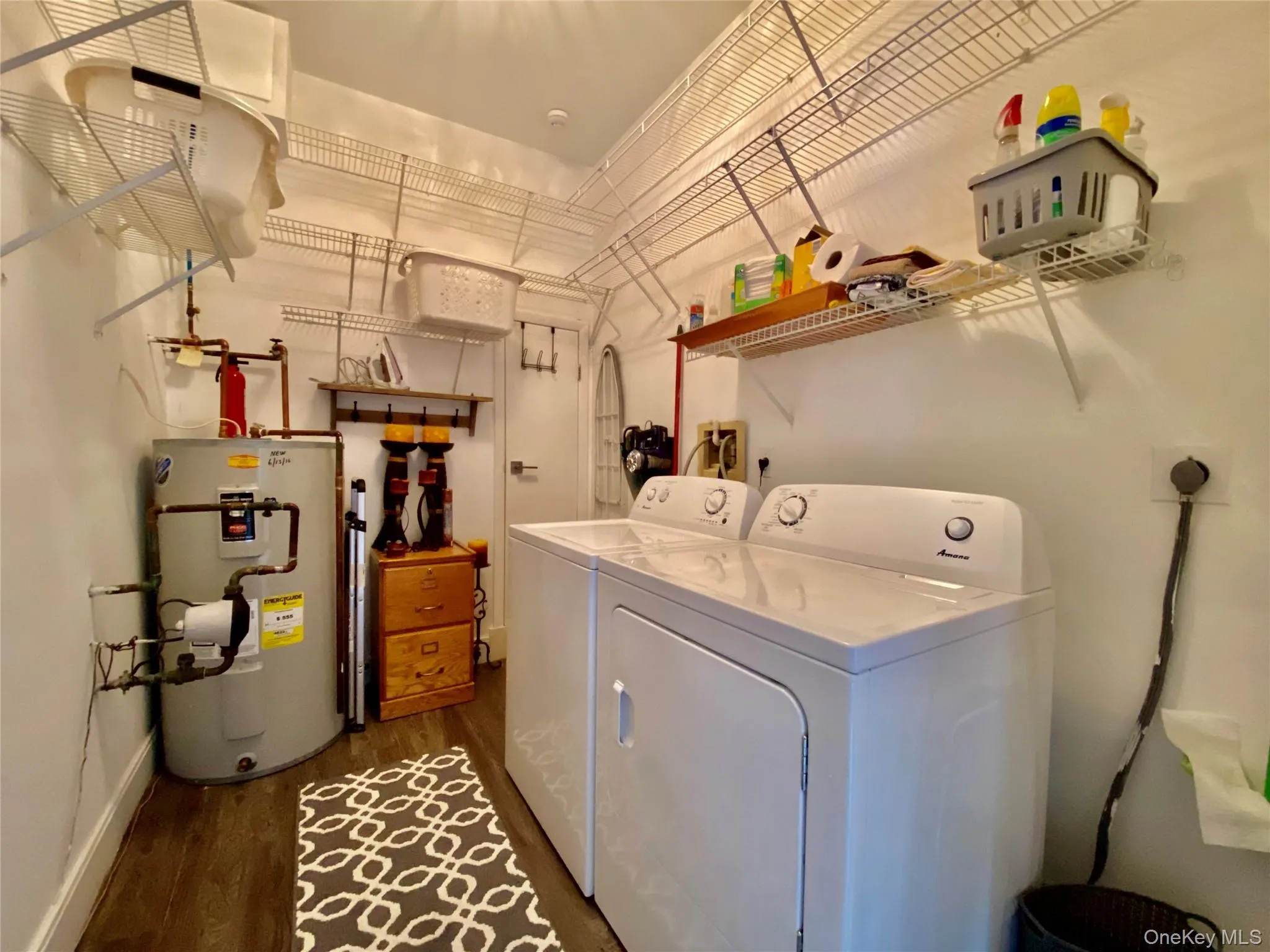 Laundry area with electric water heater, dark wood-style flooring, and washing machine and dryer Laundry area with electric water heater, dark wood-style flooring, and washing machine and dryer