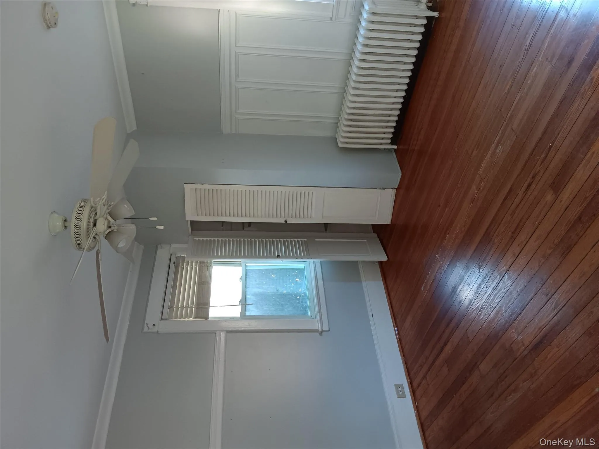 Unfurnished bedroom with radiator, crown molding, dark wood-style flooring, and ceiling fan Unfurnished bedroom with radiator, crown molding, dark wood-style flooring, and ceiling fan