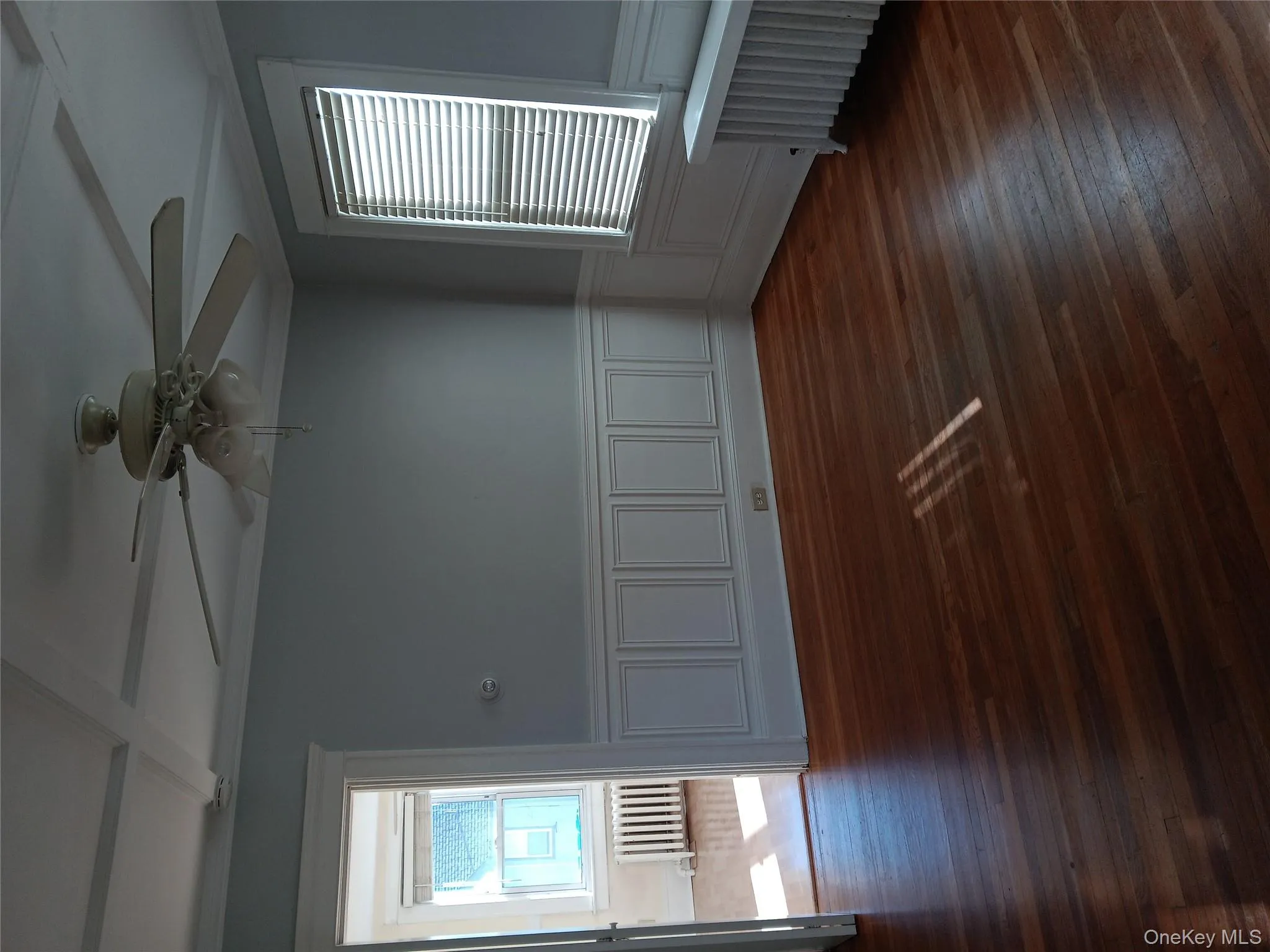 Unfurnished room with wainscoting, coffered ceiling, radiator, plenty of natural light, and dark wood finished floors Unfurnished room with wainscoting, coffered ceiling, radiator, plenty of natural light, and dark wood finished floors