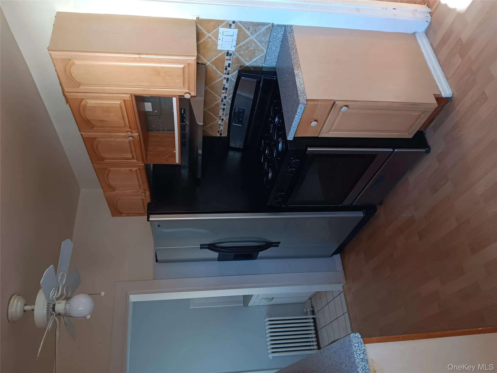 Kitchen featuring range, radiator, light brown cabinets, light wood-style flooring, and backsplash Kitchen featuring range, radiator, light brown cabinets, light wood-style flooring, and backsplash
