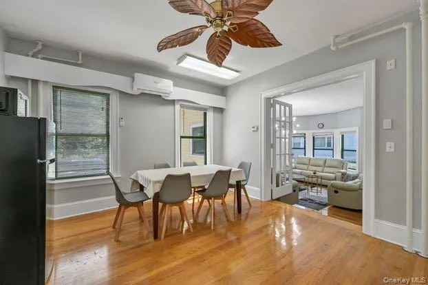 Dining area featuring ceiling fan, light wood-style floors, a wall mounted air conditioner, and french doors Dining area featuring ceiling fan, light wood-style floors, a wall mounted air conditioner, and french doors