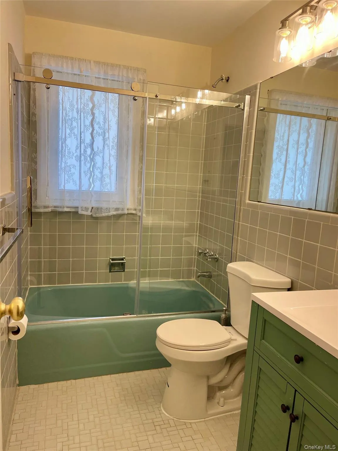 Full bath featuring washtub / shower combination, vanity, tile walls, and healthy amount of natural light Full bath featuring washtub / shower combination, vanity, tile walls, and healthy amount of natural light