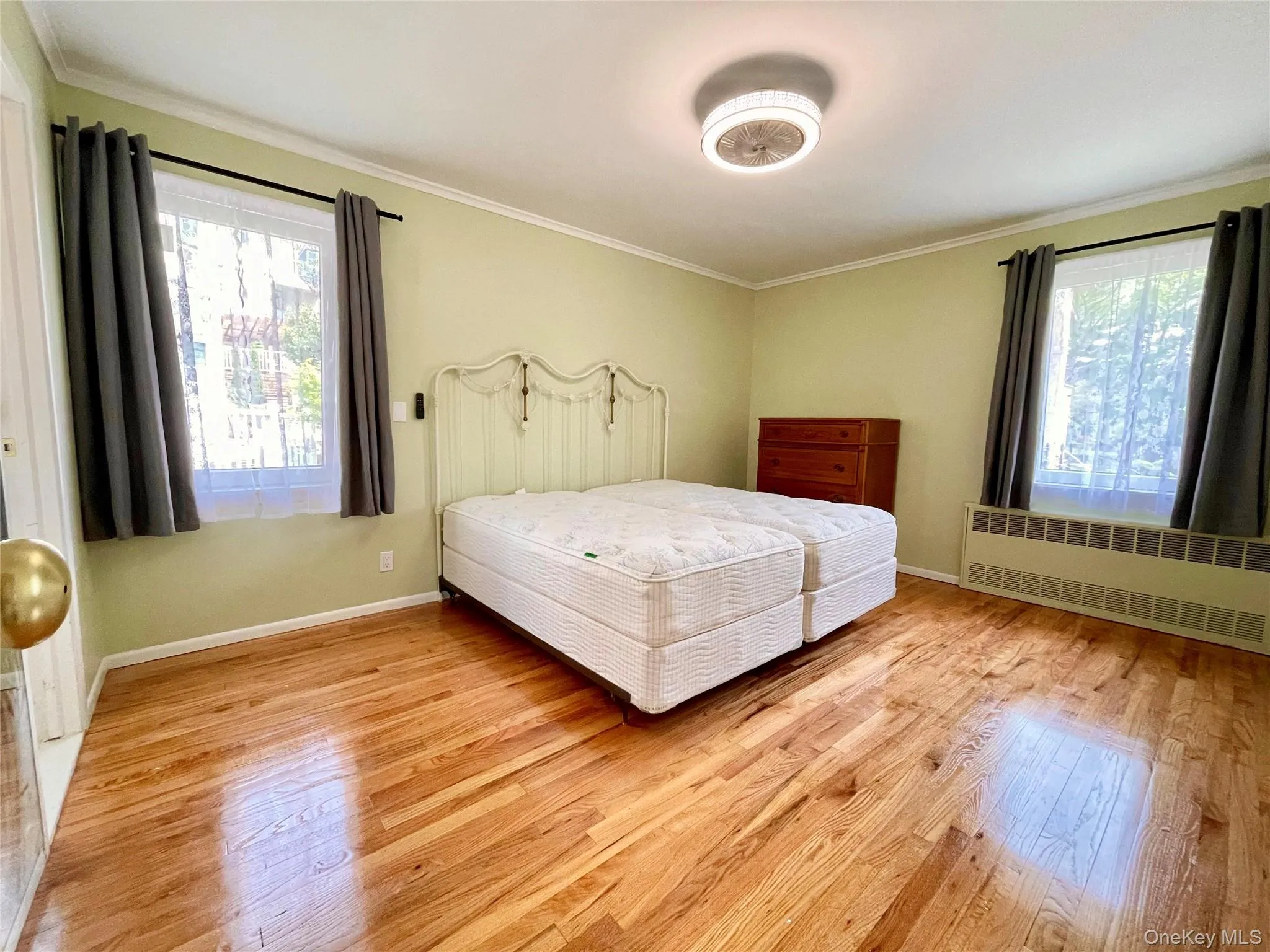 Bedroom with radiator, ornamental molding, and light wood-style floors Bedroom with radiator, ornamental molding, and light wood-style floors