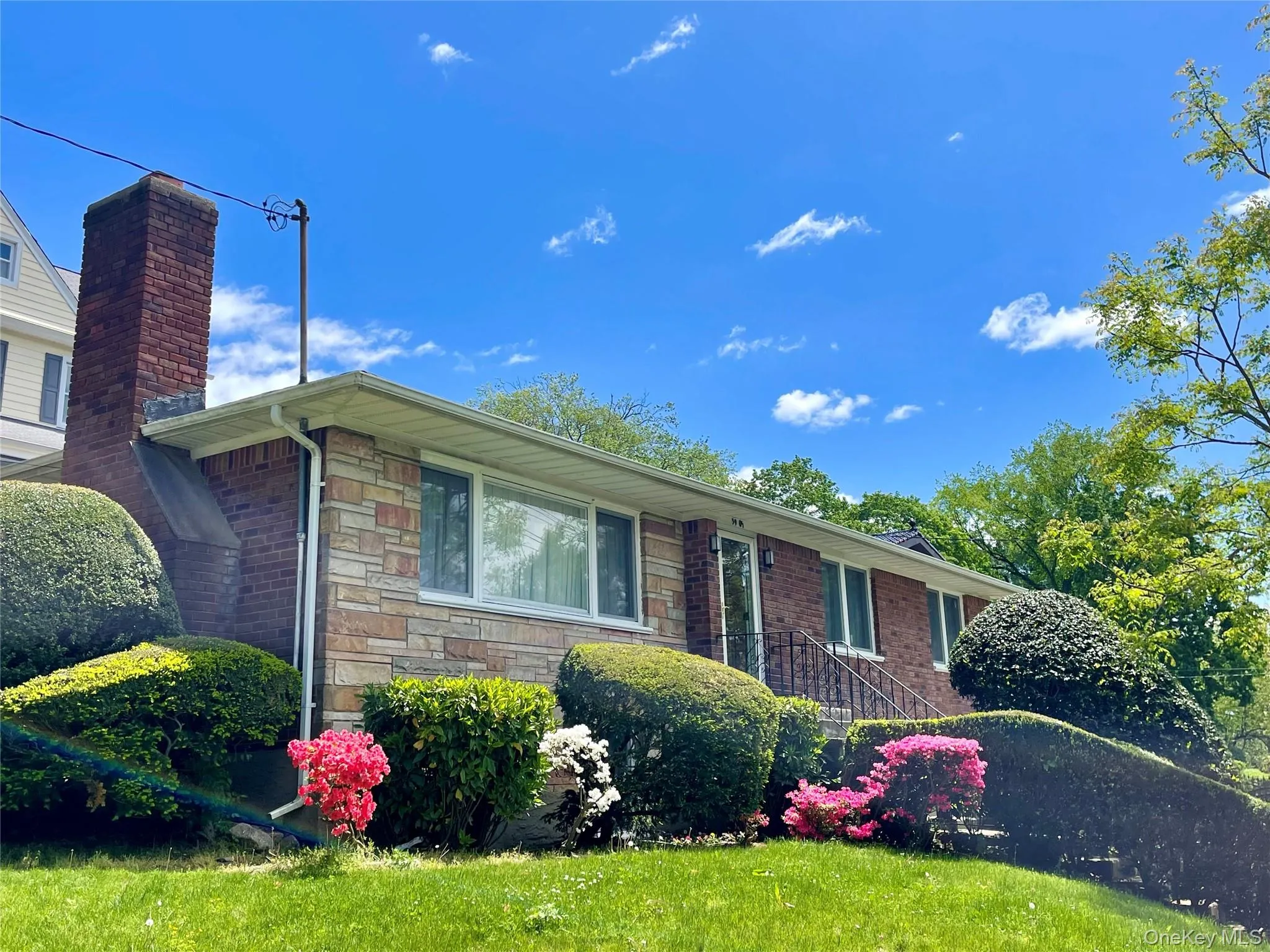 Single story home featuring stone siding, a front yard, and a chimney Single story home featuring stone siding, a front yard, and a chimney