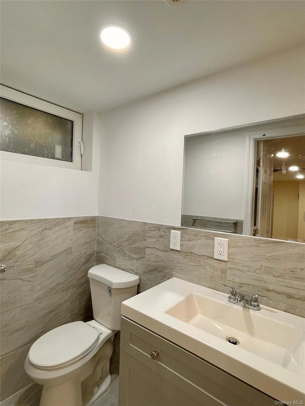Bathroom with tile walls, vanity, and wainscoting Bathroom with tile walls, vanity, and wainscoting