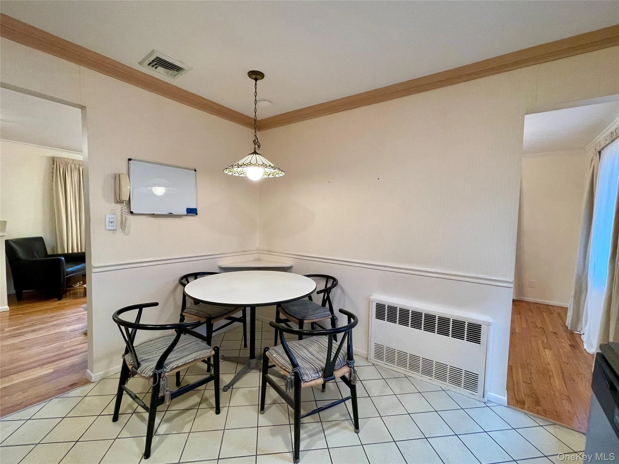 Dining space featuring ornamental molding, radiator heating unit, and light tile patterned flooring Dining space featuring ornamental molding, radiator heating unit, and light tile patterned flooring