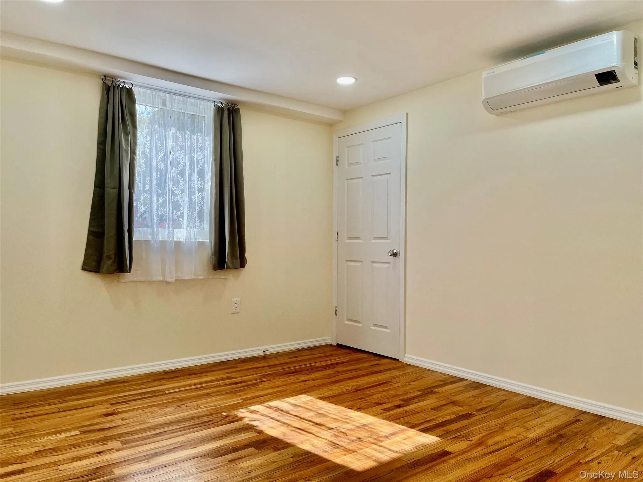 Spare room featuring a wall unit AC, light wood-style floors, and recessed lighting Spare room featuring a wall unit AC, light wood-style floors, and recessed lighting