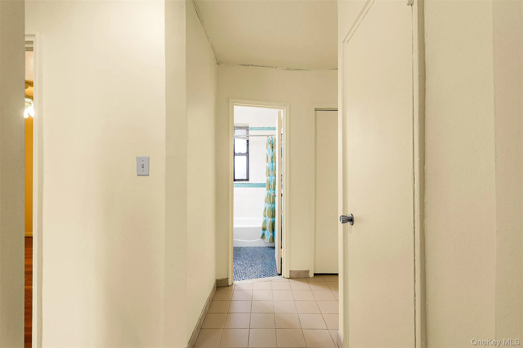 Hallway featuring light tile patterned flooring and baseboards Hallway featuring light tile patterned flooring and baseboards