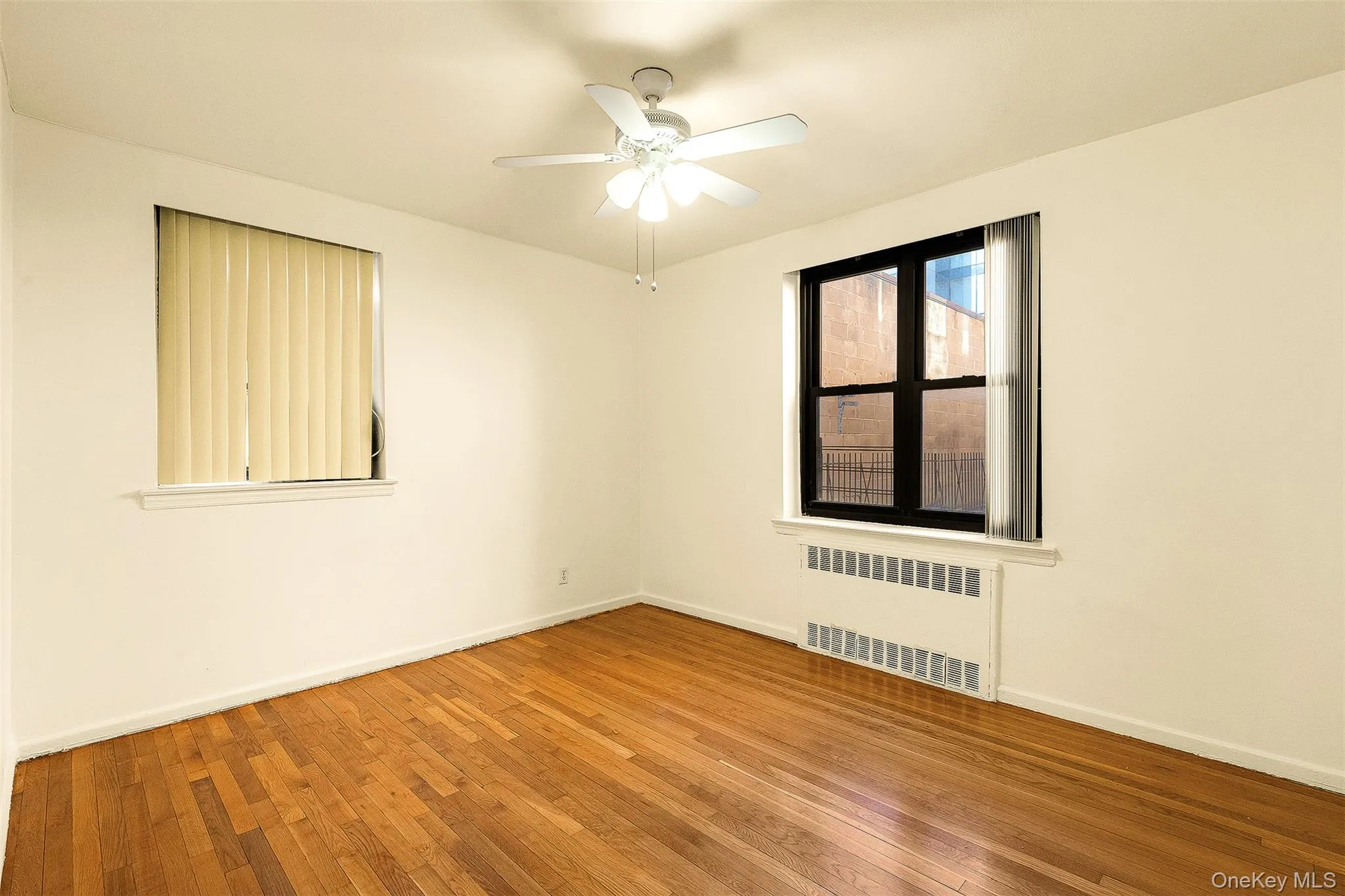 Unfurnished room with radiator, hardwood / wood-style floors, and ceiling fan Unfurnished room with radiator, hardwood / wood-style floors, and ceiling fan