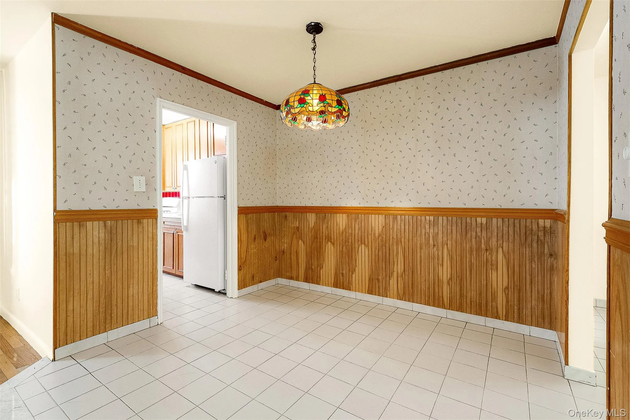 Unfurnished dining area featuring wood walls, wallpapered walls, a wainscoted wall, and light tile patterned flooring Unfurnished dining area featuring wood walls, wallpapered walls, a wainscoted wall, and light tile patterned flooring