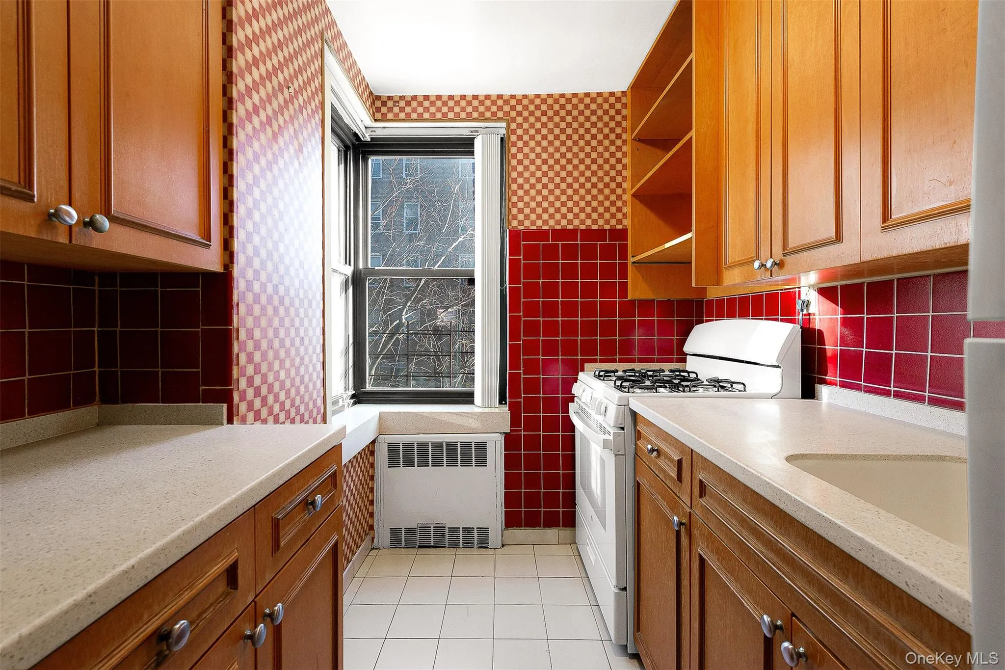 Kitchen with gas range gas stove, brown cabinetry, open shelves, radiator heating unit, and wallpapered walls Kitchen with gas range gas stove, brown cabinetry, open shelves, radiator heating unit, and wallpapered walls