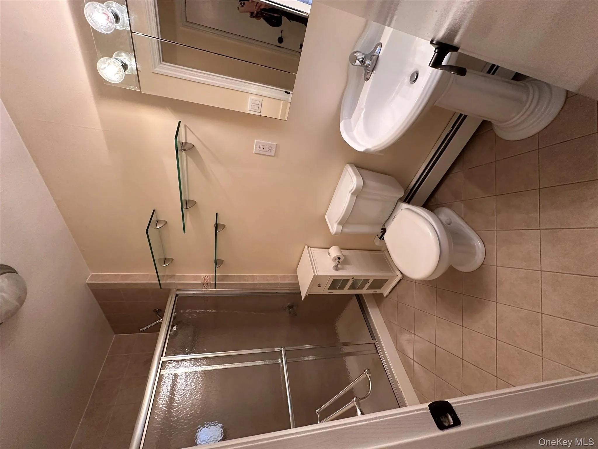 Full bath featuring a shower stall, light tile patterned floors, and a baseboard radiator Full bath featuring a shower stall, light tile patterned floors, and a baseboard radiator