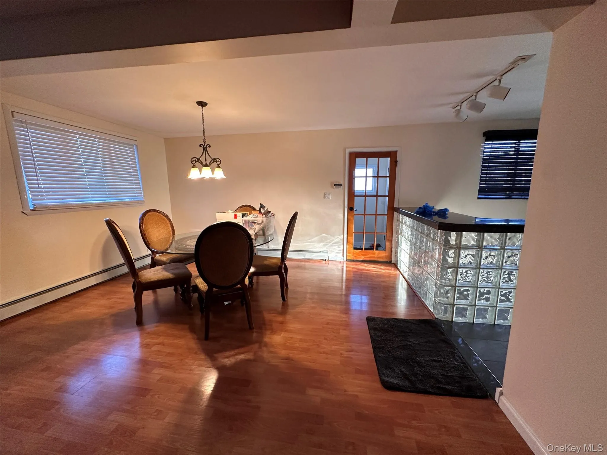 Dining area featuring wood finished floors, a chandelier, a baseboard heating unit, and track lighting Dining area featuring wood finished floors, a chandelier, a baseboard heating unit, and track lighting