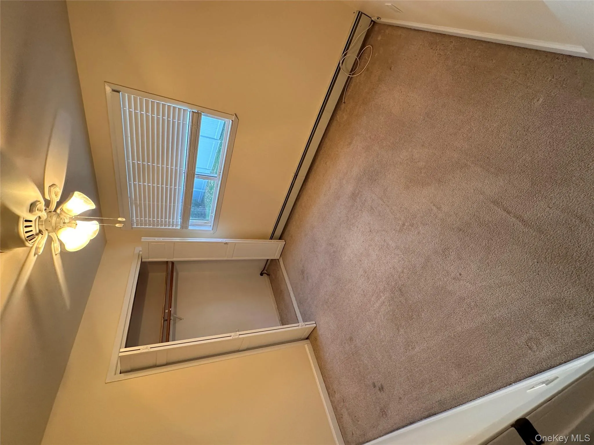 Unfurnished bedroom with baseboard heating, ceiling fan, light carpet, and a closet Unfurnished bedroom with baseboard heating, ceiling fan, light carpet, and a closet