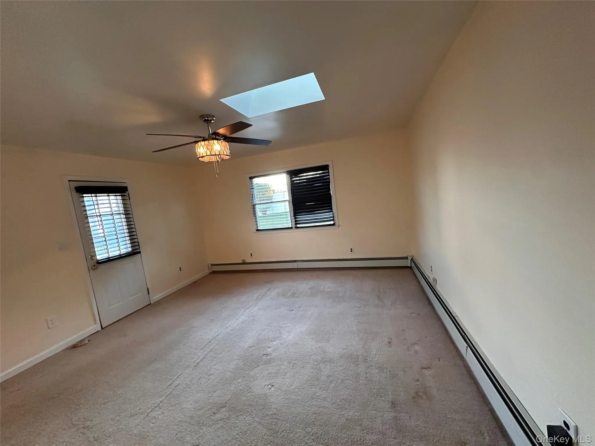Carpeted spare room featuring a skylight and a baseboard radiator Carpeted spare room featuring a skylight and a baseboard radiator