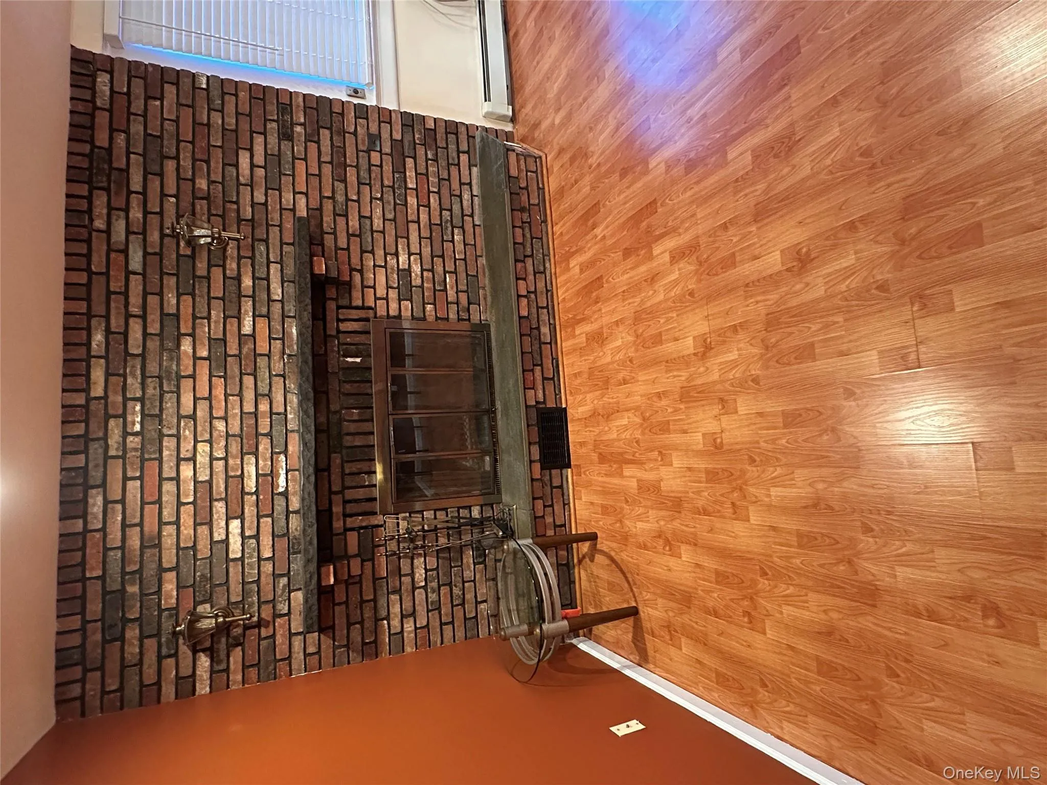 Unfurnished living room featuring a fireplace, wood finished floors, and a baseboard heating unit Unfurnished living room featuring a fireplace, wood finished floors, and a baseboard heating unit