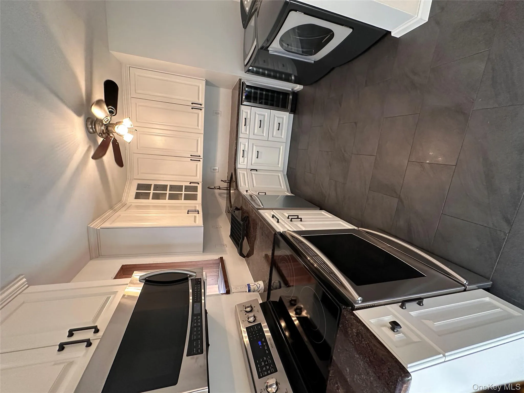 Kitchen featuring appliances with stainless steel finishes, wine cooler, white cabinets, and glass insert cabinets Kitchen featuring appliances with stainless steel finishes, wine cooler, white cabinets, and glass insert cabinets