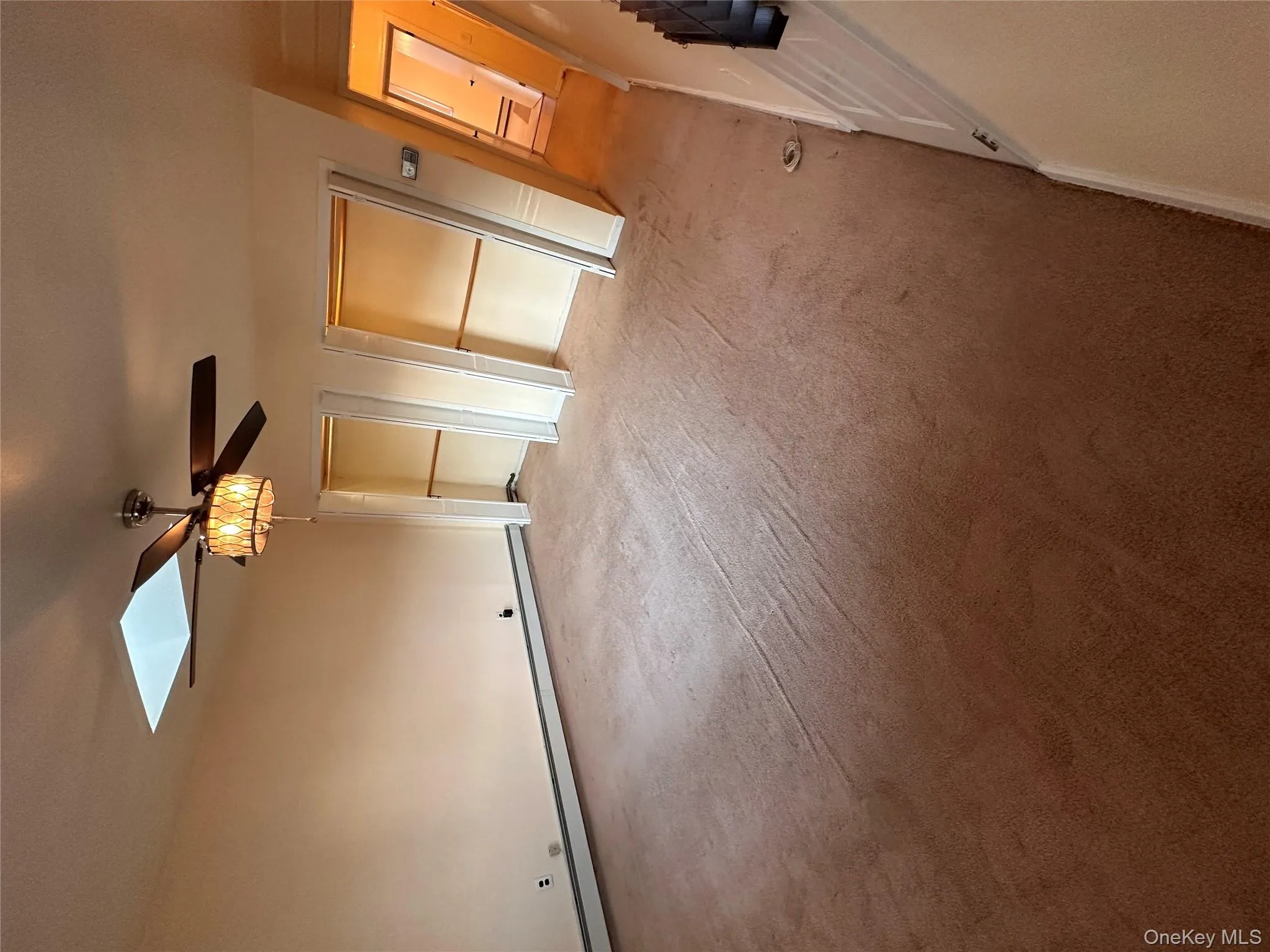 Unfurnished bedroom with a skylight, light carpet, multiple closets, baseboard heating, and ceiling fan Unfurnished bedroom with a skylight, light carpet, multiple closets, baseboard heating, and ceiling fan