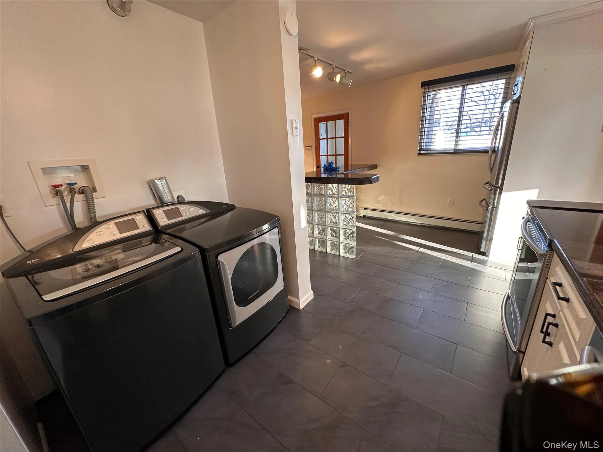 Laundry area with a baseboard heating unit, washing machine and clothes dryer, and rail lighting Laundry area with a baseboard heating unit, washing machine and clothes dryer, and rail lighting