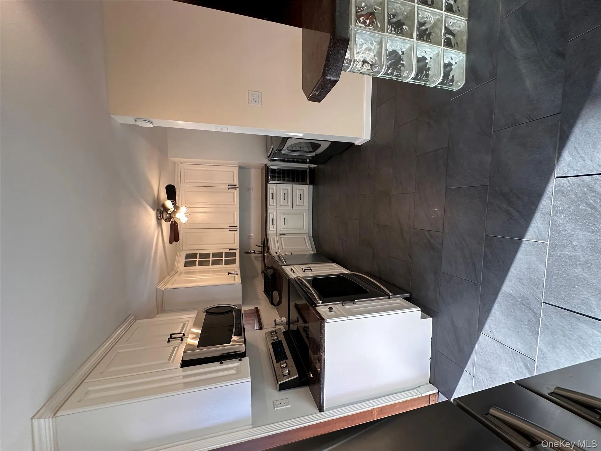 Kitchen featuring stainless steel range, glass insert cabinets, white cabinets, wine cooler, and independent washer and dryer Kitchen featuring stainless steel range, glass insert cabinets, white cabinets, wine cooler, and independent washer and dryer