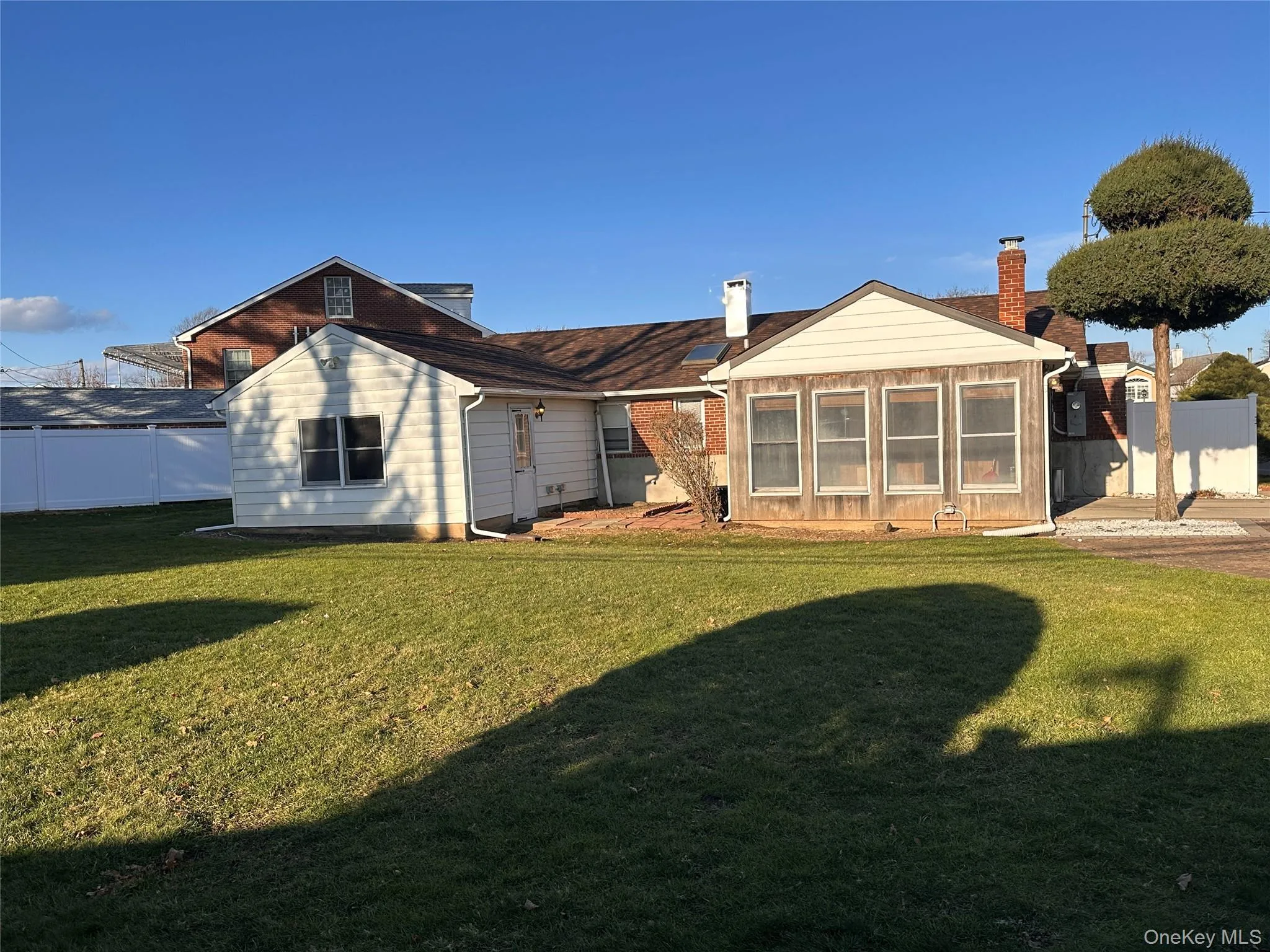 Back of property featuring a sunroom and a chimney Back of property featuring a sunroom and a chimney