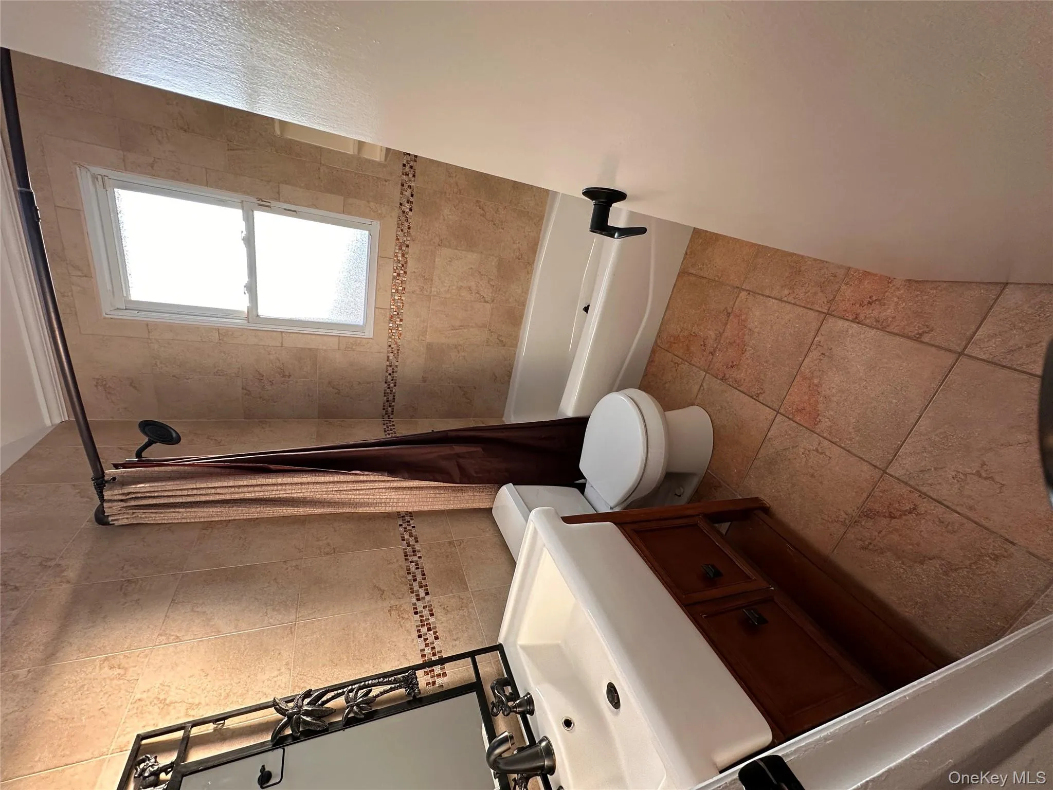 Bathroom with tile walls, vanity, and shower / bathtub combination with curtain Bathroom with tile walls, vanity, and shower / bathtub combination with curtain
