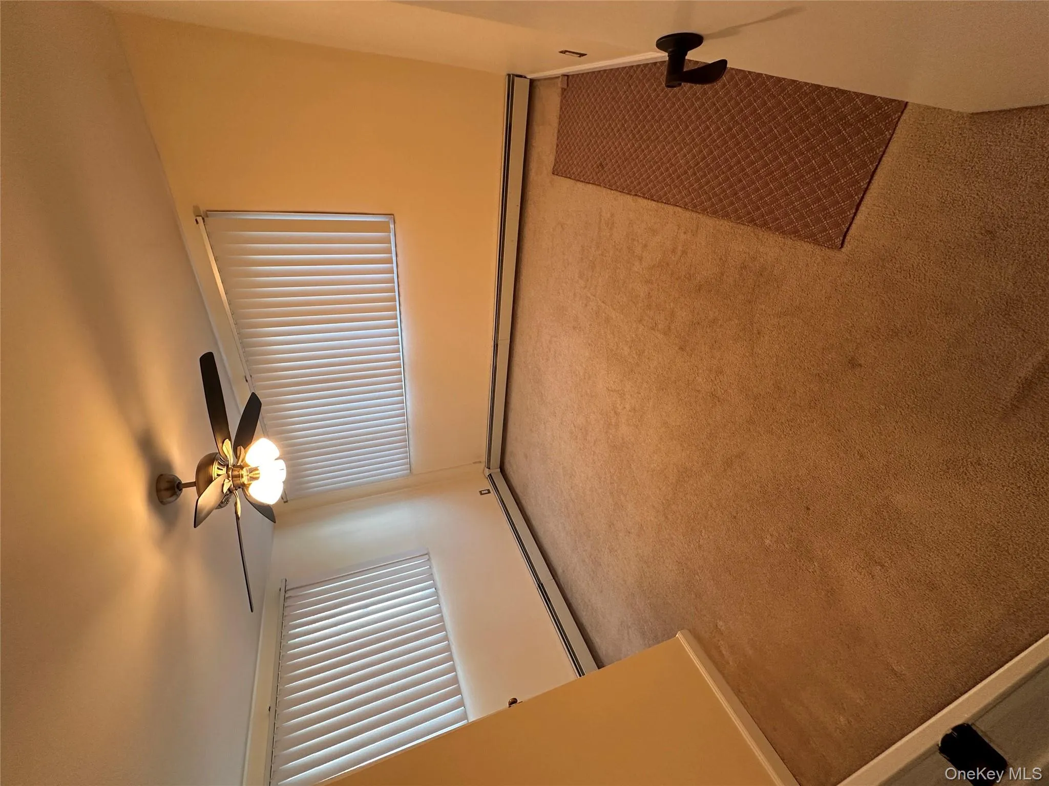 Carpeted empty room featuring baseboard heating and a ceiling fan Carpeted empty room featuring baseboard heating and a ceiling fan